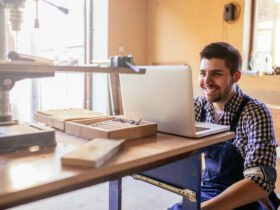 Ein Handwerker sitzt in der Werkstatt und schaut auf ein Notebook